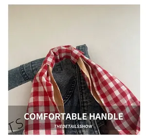Detail of red and white plaid fabric handles on a lightweight canvas tote bag