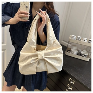 Gros plan du sac cabas crème en forme de nœud montrant la texture plissée et le grand nœud