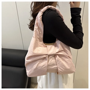 Détail du sac à bandoulière rose clair au design de grand nœud en tissu à texture froissée