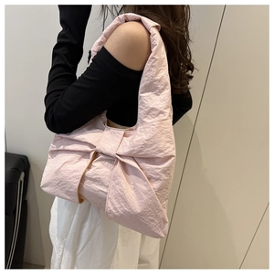 Detail of light pink shoulder bag featuring a stylish bow design and pleated fabric texture
