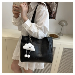 Détail d'un sac cabas noir à coutures géométriques et charm peluche nuage blanc