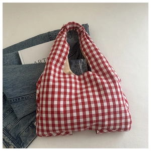 Detail of red and white checkered canvas tote bag with reinforced handles on denim jacket