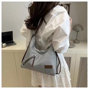 Detailed texture view of a herringbone fabric tote bag worn on a white blouse