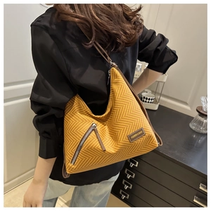 Detail of yellow herringbone hobo bag featuring silver zipper and fashion label
