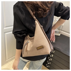 Detail of brown herringbone tote bag with leather strap and fashion label on a model