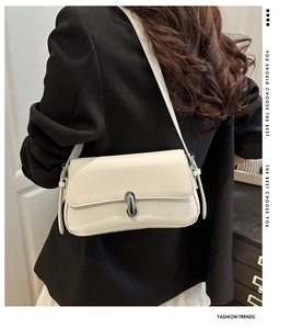 Detail of cream white leather underarm bag featuring a stylish silver metal capsule buckle