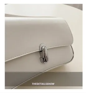 Detailed close-up of the silver metal clasp and neat stitching on a white leather bag