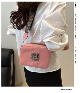Detail of pink rectangular crossbody bag with SM metal logo and wide woven strap