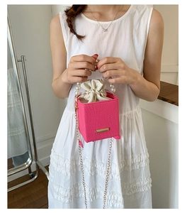 Pink faux crocodile leather bucket bag with pearl handle and golden chain detail