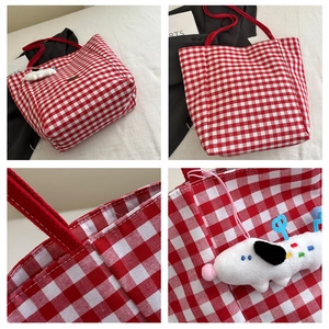 Detail van rood geruite canvas draagtas met pluchen puppy-hanger en stevige handvatten