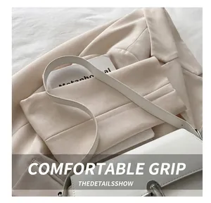 Detail of white leather shoulder bag with silver buckle on a beige blazer background