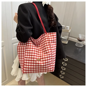 Detail of red and white checkered canvas tote bag with a handmade metal tag detail