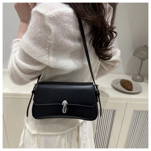 Close-up of a minimalist black leather underarm bag with a silver metal clasp closure
