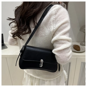 Chic black underarm bag with silver metallic buckle worn with a white sweater