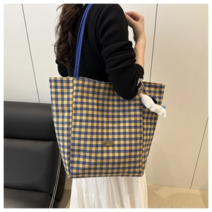 Detail of checkered canvas tote bag with blue strap and cute white puppy plush charm