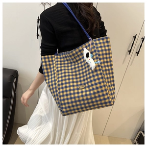 Close-up of yellow and blue plaid tote bag with handmade metal tag and puppy charm
