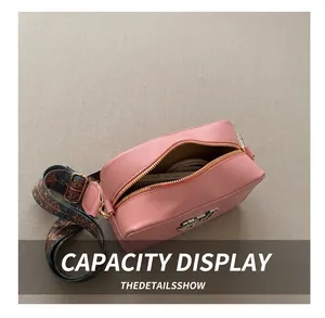 Pink square leather crossbody bag with wide patterned strap and metal logo detail