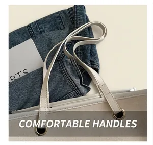 Detailed close-up of a white canvas tote bag with leather straps and metal eyelet accents