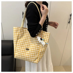 Detail of yellow plaid canvas tote bag with shoulder strap and plush dog keychain