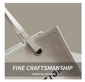 Detail of canvas tote bag showing reinforced leather edge and metal eyelet handles