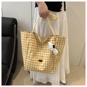 Detail van een geel geblokte tote bag met een schattige witte pluche puppy sleutelhanger