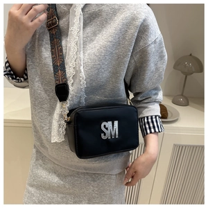 Detail of black crossbody bag with rhinestone SM logo and vintage colorful woven strap