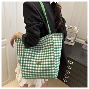 Detail van groene gingham canvas shopper met handgemaakte metalen badge en geweven handvat