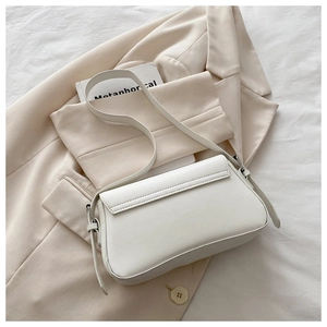 Detail of white faux leather underarm bag featuring smooth texture and metal strap rings