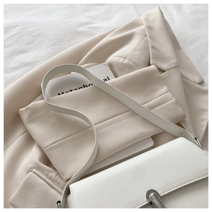 Detail of white leather shoulder bag with a modern silver rotating metal lock clasp