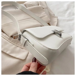 Detail of ivory faux leather shoulder bag with silver clasp on chic neutral background