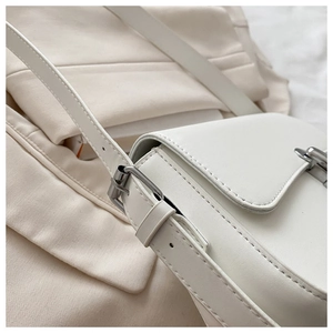 Detail of white leather shoulder bag featuring fine stitching and silver metal hardware