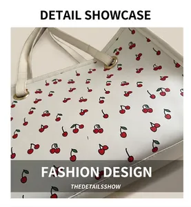 Detail of white tote bag with red cherry print and golden metal buckle hardware