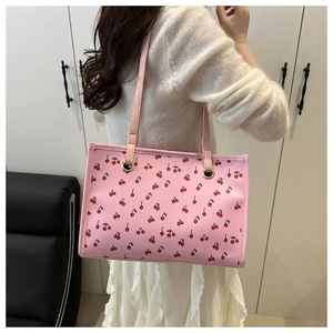 Detail of pink tote bag with cherry print shown on shoulder for size reference
