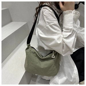 Detail of sage green crescent bag showing nylon texture and white triangle zipper pull