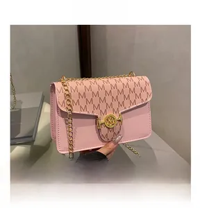 Detailed macro view of pink textured leather bag with gold M-logo clasp and chain strap
