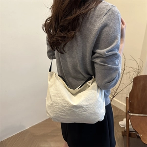 Minimalist beige nylon hobo crossbody bag with pleated texture and black adjustable strap