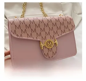 Detail of pink leather crossbody bag with embossed M texture and gold logo clasp