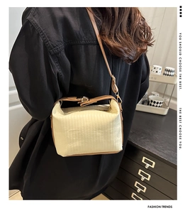 Detail showing the pleated fabric texture and brown leather strap on the shoulder bag