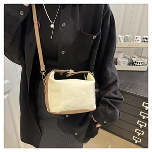 Close-up of cream textured fabric handbag with brown leather trim and metal buckles