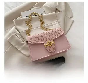 Detail of pink flap bag featuring gold chain strap and textured M pattern print