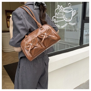 Detail shot of brown faux leather shoulder bag featuring aesthetic bow pockets on a model