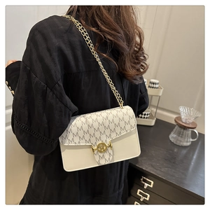 Detail of cream crossbody bag featuring M-pattern print and golden double chain strap