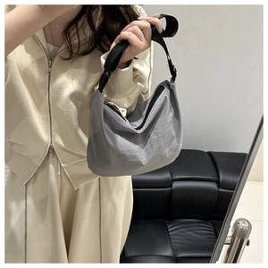 Detail of grey crescent shoulder bag with black adjustable strap and textured nylon fabric