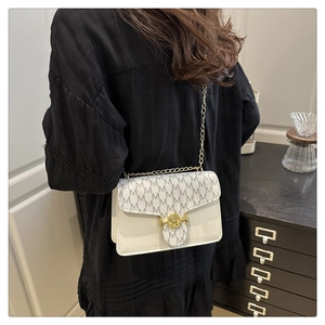 Detail view of white crossbody bag with grey M pattern and gold chain strap on model