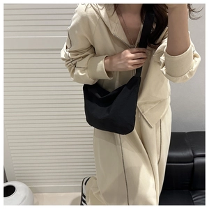 Minimalist black crescent canvas crossbody bag worn with a beige tracksuit for a casual look