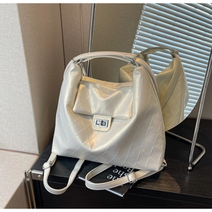 Détail d'un sac à dos matelassé crème avec fermoir rotatif argenté et finition en cuir PU