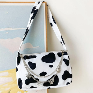 Retro canvas underarm bag with black and white cow print and butterfly chain detail