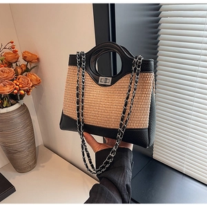 Détail du sac seau en paille tressée avec bordure en cuir noir et fermoir tournant