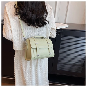 Detail of light green vintage crossbody bag with flap and metal tip straps on model