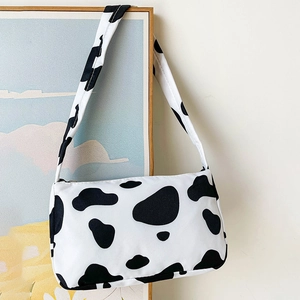 Retro cow print canvas underarm bag with black and white spots and single shoulder strap